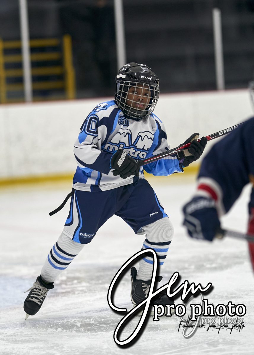 Joueur de hockey en patin, chandail blanc et bleu