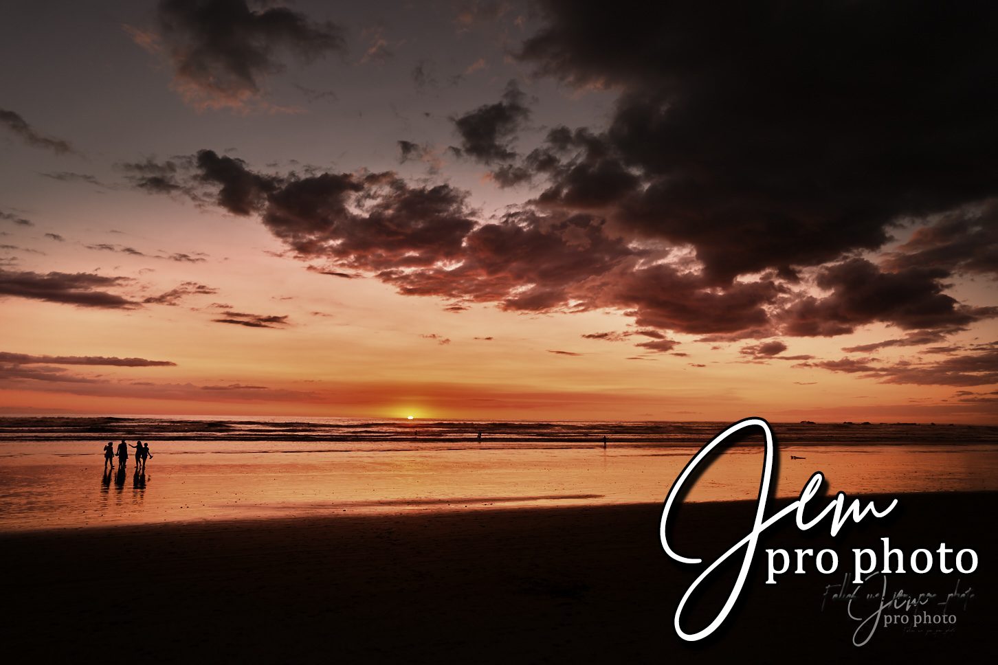 Coucher de soleil sur une plage, silhouettes au loin