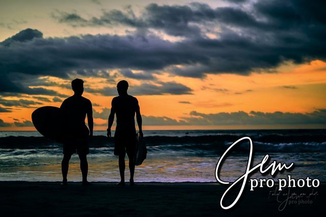 Deux surfeurs de dos face à la mer au crépuscule